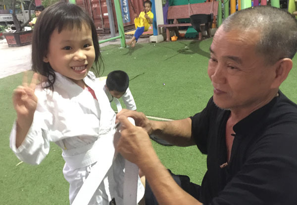 Ông Hiệp mặc áo cho con gái khi bé đi học võ