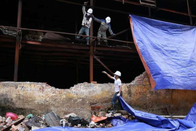 Công nhân phủ bạt quanh nhà kho bị cháy chiều 4/9. Ảnh: Tất Định 