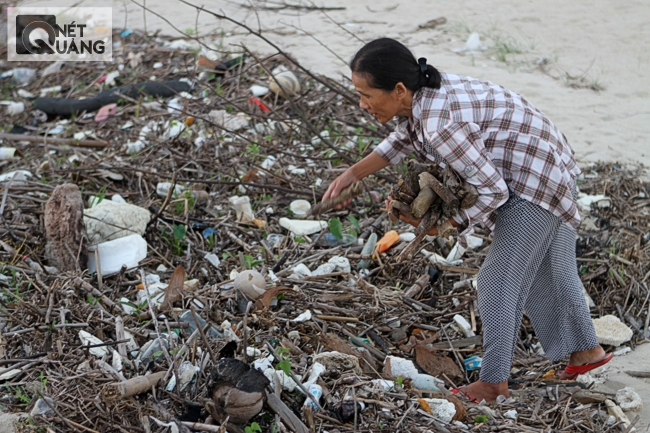 Một người đàn bà đang đi mót củi ngay cửa sông Cu Đê. Rác từ biển vào theo từng cơn sóng đánh, từ sông chảy ra biển còn có ra cả rác sử dụng được.