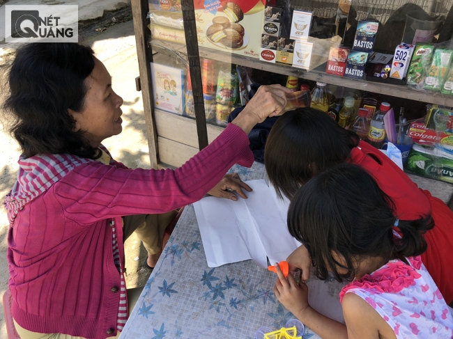 Một người phụ nữ đang bắt chí cho các cháu của mình. Chị có một quầy nước nho nhỏ ven đường, bán nước cho du khách ghé làng để thăm biển Rạng Nam Ô.