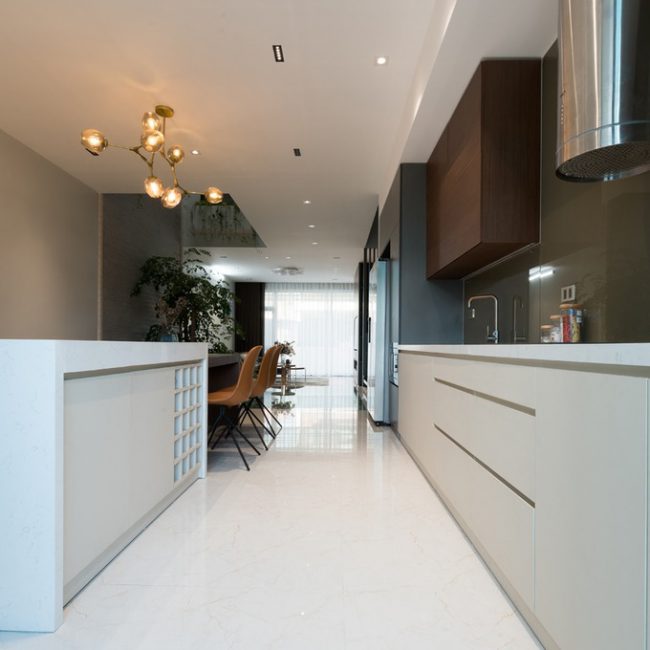 Để tạo cảm giác thông thoáng, không gian tầng một hạn chế tối đa các vách ngăn. Các khu tiếp khách, ăn uống và bếp liên thông kéo dài theo chiều dọc miếng đất.