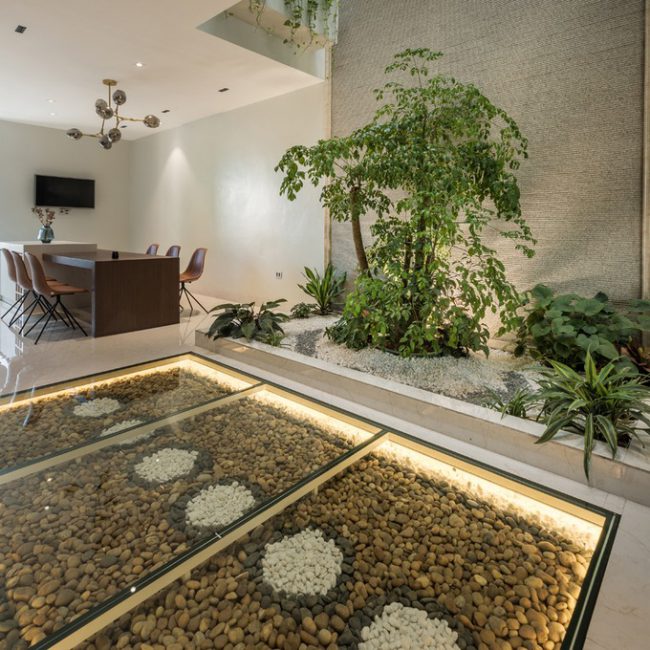 Ngay dưới chân cầu thang là một thảm sỏi rộng 7,5 m2 được trải trên nền bê tông và phủ kính cường lực dày 15mm. Kế đó là một khu tiểu cảnh rộng 6m2 với cây hạnh phúc cao 2,5m, tượng trưng cho tình cảm của đôi vợ chồng trẻ sắp cưới.