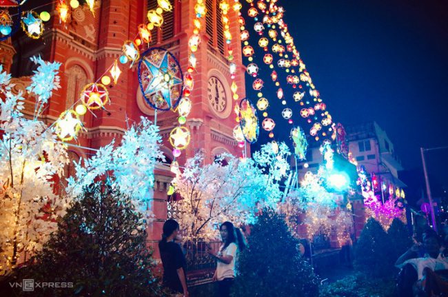 Dàn đèn nhiều màu sắc được giăng từ đỉnh tháp chuông xuống cổng chính, kết hợp với những cành cây trắng như phủ tuyết tạo nên khung cảnh huyền ảo, thu hút nhiều khách tham quan và chụp ảnh vào buổi tối.