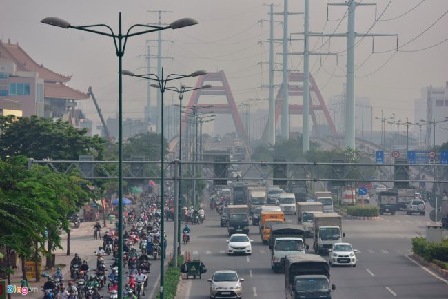 "Độ ẩm hiện nay rất thấp, chỉ khoảng 60-70%, làm sao có sương mù được. Sương mù phải hơn 90% trở lên. Vậy nên đây có thể là mù khô do ô nhiễm", chuyên gia thời tiết Lê Thị Xuân Lan phân tích. Người dân di chuyển trong bầu không khí mờ ảo ở đường Phạm Văn Đồng. Ành: Lê Quân.