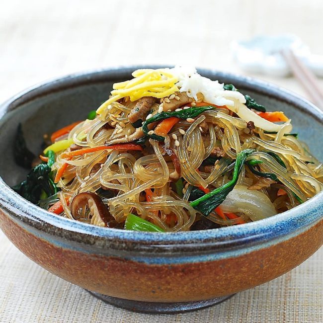 Japchae là món miến trộn có xuất xứ từ Hàn Quốc. Ngoài sợi miến, món ăn này còn bao gồm nhiều thành phần khác như cà rốt, mộc nhĩ, nấm hương, hành tây, rau xanh… được đem xào chung với dầu mè và nước tương. Japchae này có thể thưởng thức nóng hoặc nguội hoặc dùng như món ăn kèm với cơm. Ảnh: Okonomikitchen, koreanbapsang.
