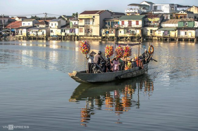 Người dân vận chuyển những chồng hoa trên bến đò ngang Bao Vinh. Phía sau là dãy nhà cổ Bao Vinh, thuộc xã Hương Vinh, thị xã Hương Trà.