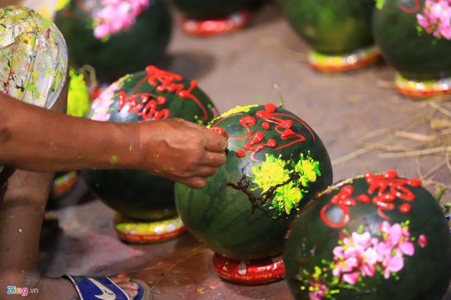 Rạng sáng 25 Tết, trên vỉa hè đường Thành Thái (quận 5, TP.HCM), ông Bá Lâm, nghệ nhân vẽ tranh trên hoa quả, miệt mài vẽ những câu đối Tết trên trái dưa hấu được chuyển lên từ Long An. "Mỗi trái như vậy tôi vẽ mất 15-20 phút và được tính công 100.000 đồng, những cặp dưa sau khi hoàn thành được chủ vựa bán tới 800.000 đồng"