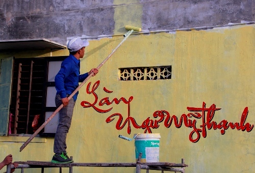 Nhóm bạn trẻ quét sơn lên tường nhà ở làng Ngư Mỹ Thạnh. 