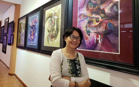 Họa sĩ Dư Dư bên các tác phẩm của mình tại triển lãm Trở về - Ảnh: THÁI LỘC