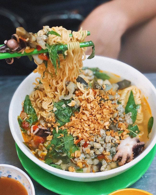 Mì ốc hến Dì Lan: Một sự kết hợp khá lạ trong ẩm thực TP.HCM, mì ốc hến gồm có mì gói chín vừa, ốc móng tay, hến, bạch tuộc, tôm... cùng với nước dùng đậm đà, tỏi phi và rau thơm. Không gian quán rộng rãi, thoải mái, món ăn này là sự lựa chọn tuyệt vời cho những ngày mưa lạnh. Quán có nhiều chi nhánh tại quận 4, 10, Gò Vấp cho bạn lựa chọn. Giá: 28.000-43.000 đồng/suất. Ảnh: Ruahaman, choudiangi.