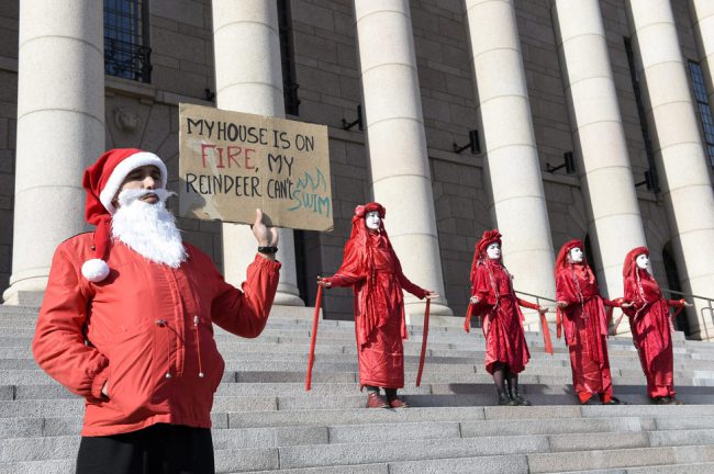 Một nhóm người ăn vận như ông già Noel giơ bảng trước tòa nhà Quốc hội Phần Lan. Dòng chữ trên bảng có ghi: "Nhà của tôi đang cháy, bầy tuần lộc của tôi lại không biết bơi", ám chỉ tình trạng nóng lên khiến băng ở Bắc cực tan nhanh