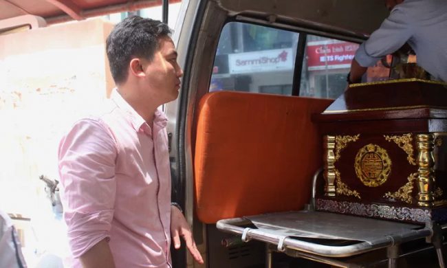 Nghị (áo hồng) nán lại với gia đình, chờ đến lúc đưa quan tài bé lên xe. Ảnh: Diệp Phan