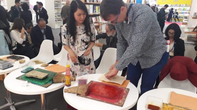 Khách thực hành làm tranh Đông Hồ tại hội sách Frankfurt.