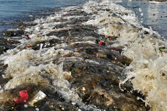 Rác dày đặc kéo dài từ bãi cát ra tận mé nước. Mỗi khi có sóng lớn, rác từ ngoài tiếp tục theo vào bờ, nhiều mảnh nhỏ bắn tung tóe.