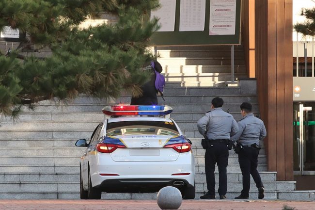 Lực lượng cảnh sát được huy động hỗ trợ thí sinh. Theo thống kê của FNNEWS, ở thành phố Seoul, khoảng 100 thí sinh đi muộn, được cảnh sát hỗ trợ đến trường thi kịp thời. Nguyên nhân chủ yếu là thí sinh ngủ quên, quên giấy tờ thi, tắc đường, nhớ nhầm điểm thi. Một nữ sinh dự thi tại điểm thi trường Trung học nữ sinh Ewha, Seoul, được hai sĩ quan cảnh sát chở đến trường kịp giờ. Ảnh: Yonhap.