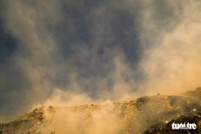 Buổi trưa, khói bốc lên từ bãi rác khiến không thể phân biệt đâu mà mây, là sương hay khói