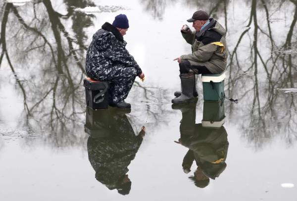 2 người đàn ông câu cá trên một hồ băng ở Nga. (Ảnh: EPA