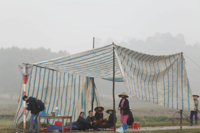 Người dân căng bạt ngồi gác không cho xe tải vào bãi rác Nam Sơn. Ảnh: Báo Giao thông