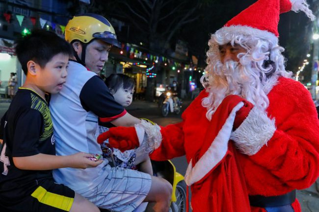 Ông Nguyễn Thế Hoàng (63 tuổi) diện trang phục ông già Noel đi tặng quà cho các em nhỏ trên đường Phạm Thế Hiển. "Cả chục năm nay, tôi đều làm việc này khi Giáng sinh. Món quà tuy nhỏ nhưng khiến các cháu vui và hạnh phúc, mình cũng vui lây", ông Hoàng nói.