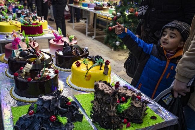 Một bé trai người Kurd cùng bố mẹ đi chọn bánh kem cho lễ đón năm mới ở thành phố Qamishli, phía bắc Syria hôm 30/12.